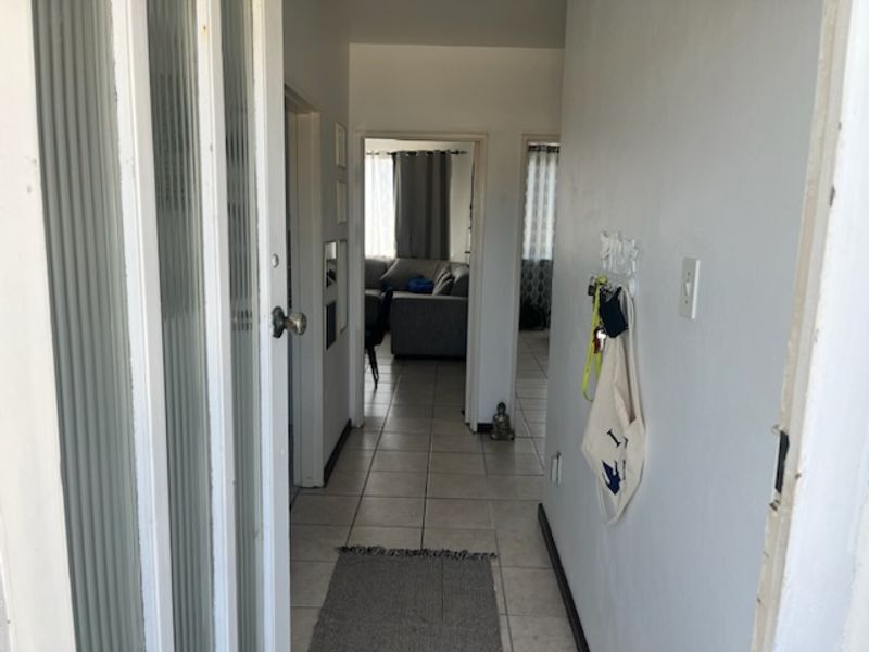 A functional hallway featuring tiled flooring and a fluted glass door, providing access to the main living areas of the apartment.