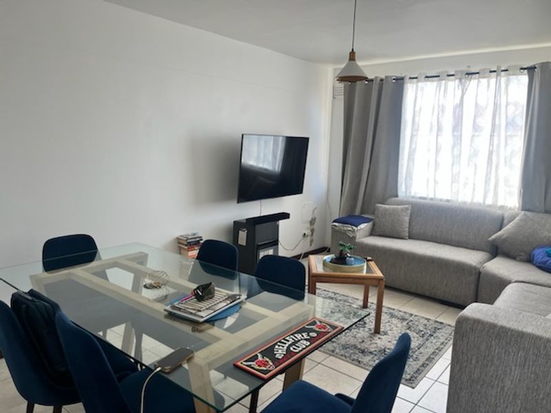 Open plan living and dining area featuring tiled flooring and neutral walls, providing a functional space for relaxation and meals.