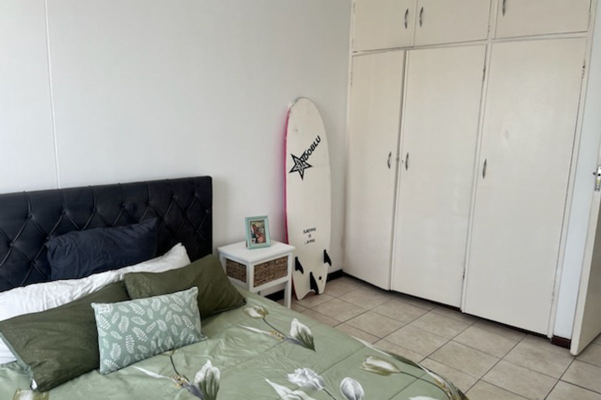A bedroom featuring tiled flooring and extensive built-in cupboard storage with overhead cabinets, offering practical space for organization.