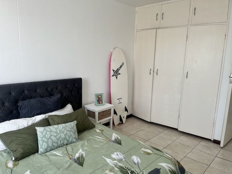 A bedroom featuring tiled flooring and extensive built-in cupboard storage with overhead cabinets, offering practical space for organization.
