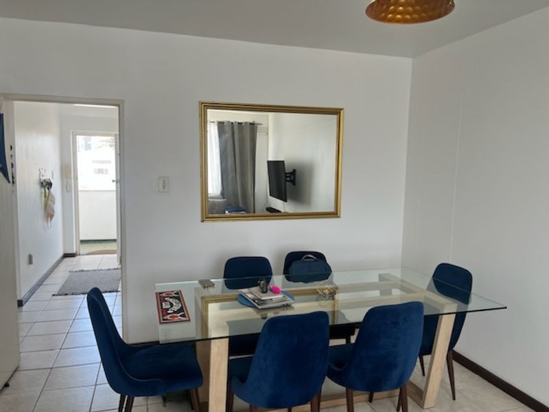A dining area featuring tiled flooring and a central pendant light fixture, providing a functional space for meals.