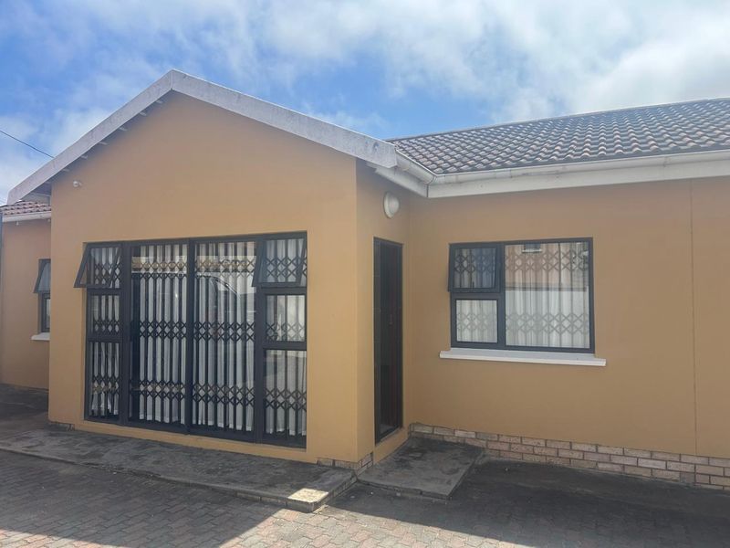 Front elevation of a single-story house featuring a tiled roof, paved driveway, and secure aluminium-framed windows with fitted security gates.