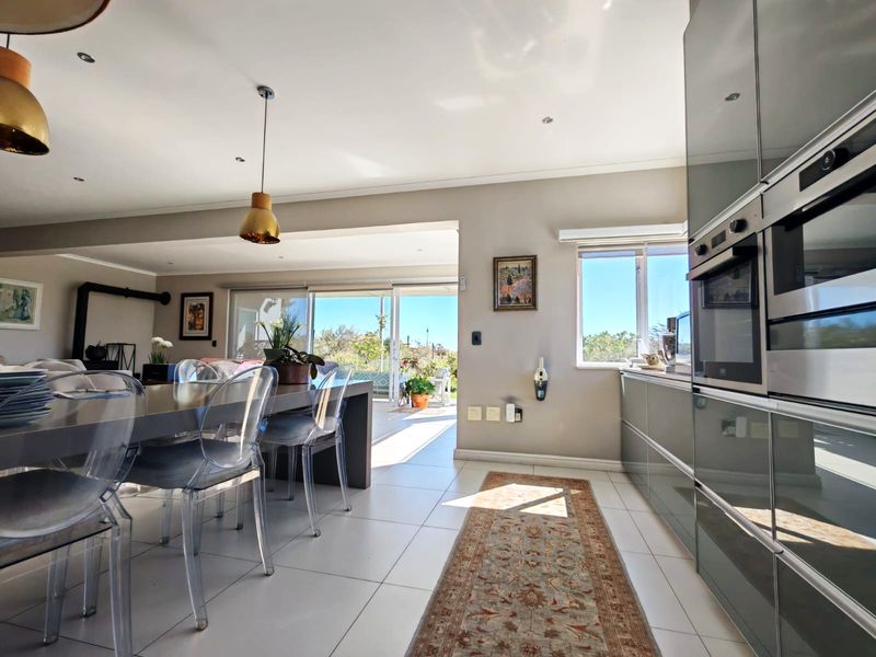 Modern open-plan living and kitchen area featuring sleek cabinetry, built-in appliances, tiled floors, and seamless access to an outdoor patio through sliding glass doors.