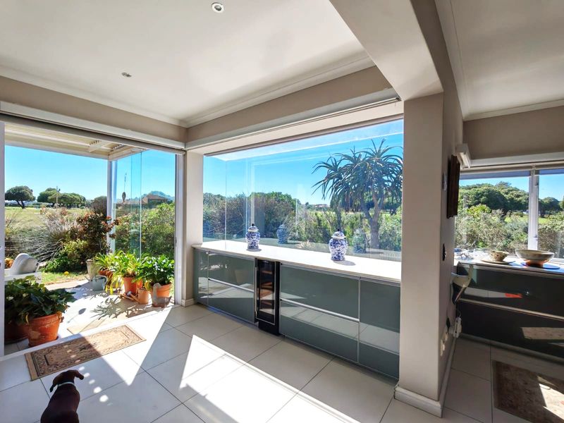Modern open-plan living area featuring sleek built-in cabinetry, an integrated wine cooler, and expansive glass sliding doors that open onto a bright patio.