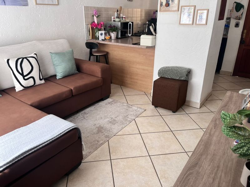 Open plan living area featuring tiled flooring and a compact kitchen breakfast bar, creating a functional and connected space.