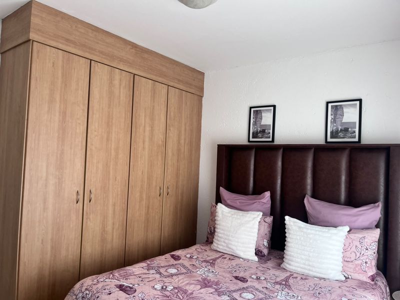 A bedroom featuring a large, light wood-finish built-in wardrobe providing ample storage space.