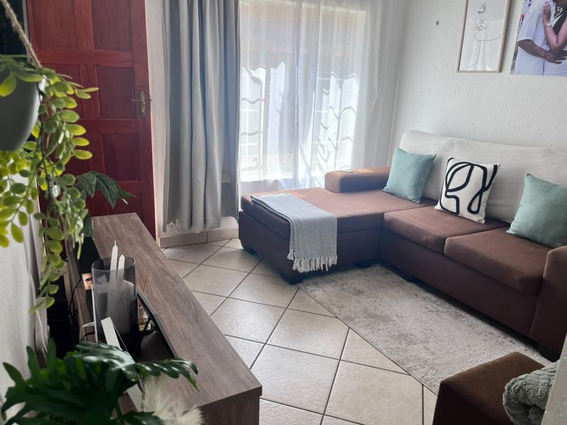 A cozy living room featuring tiled flooring and a classic timber door, providing a functional and comfortable space.