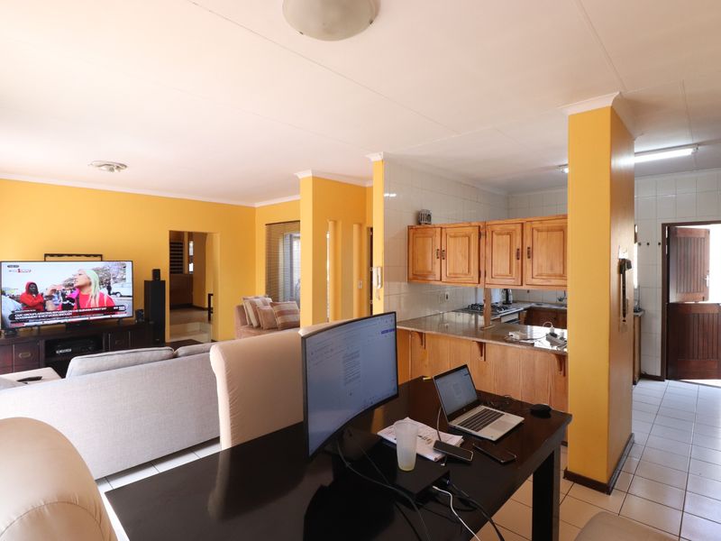 Open plan living and kitchen area featuring tiled floors, wooden cabinetry, and granite countertops, offering a functional layout with potential for modern updates.