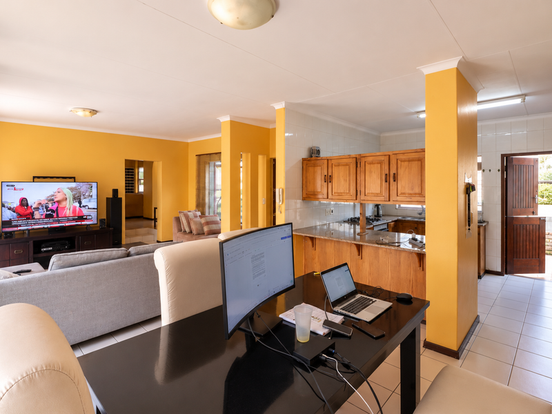 Open-plan living and kitchen area featuring tiled floors, granite countertops, and timber cabinetry, providing a functional layout with direct access to the exterior.
