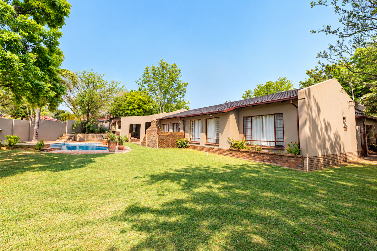 Rear view of the property featuring a well-maintained lawn, a swimming pool, and a brick-accented exterior facade with a tiled roof.