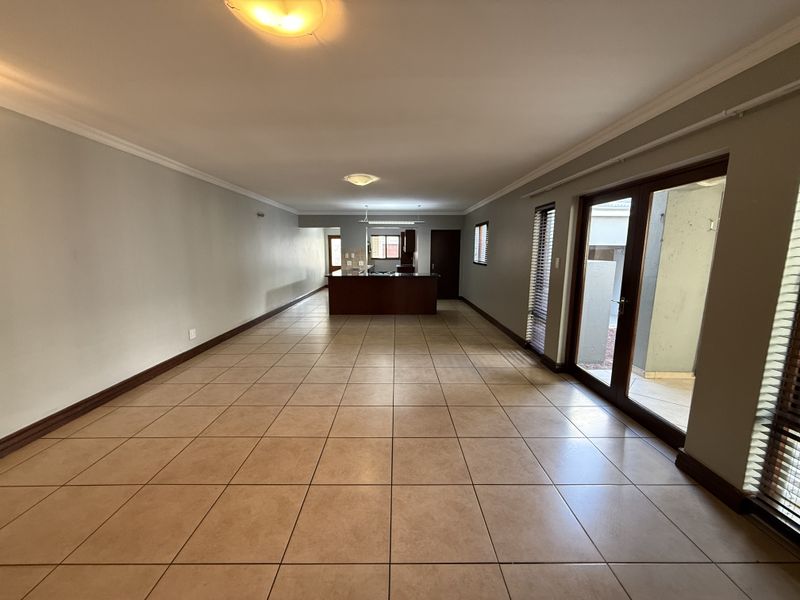 Spacious open-plan living area featuring tiled flooring, a central kitchen island, and large sliding glass doors providing access to the exterior.