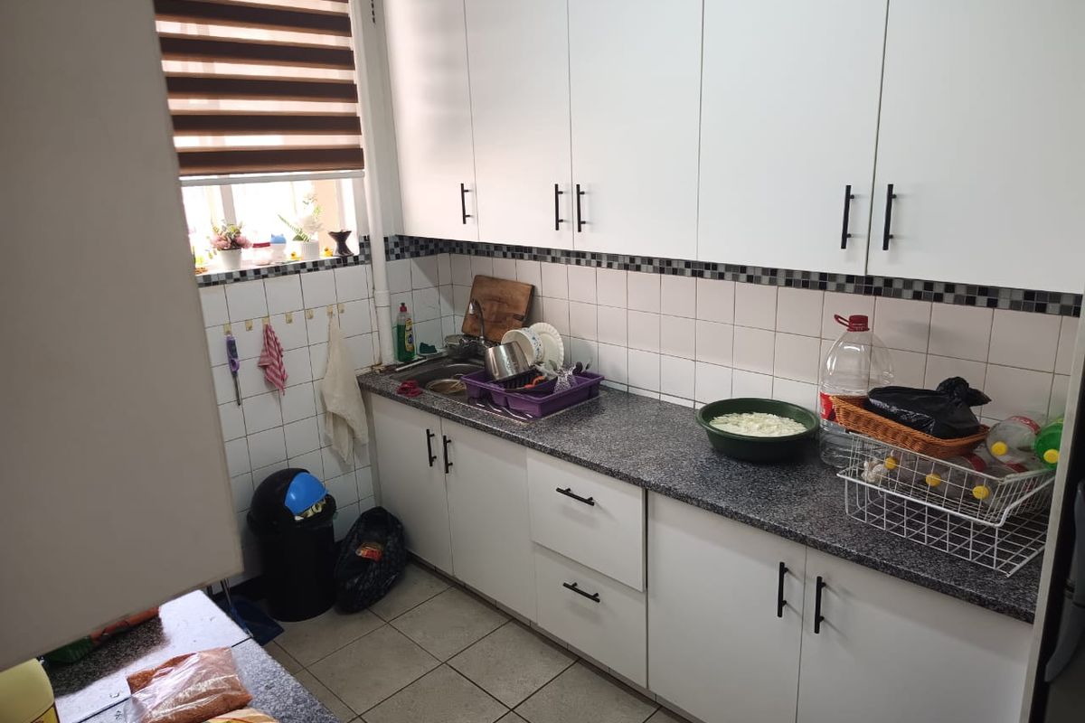 A functional kitchen featuring white cabinetry, granite countertops, a stainless steel sink, and tiled backsplash with neutral ceramic flooring.