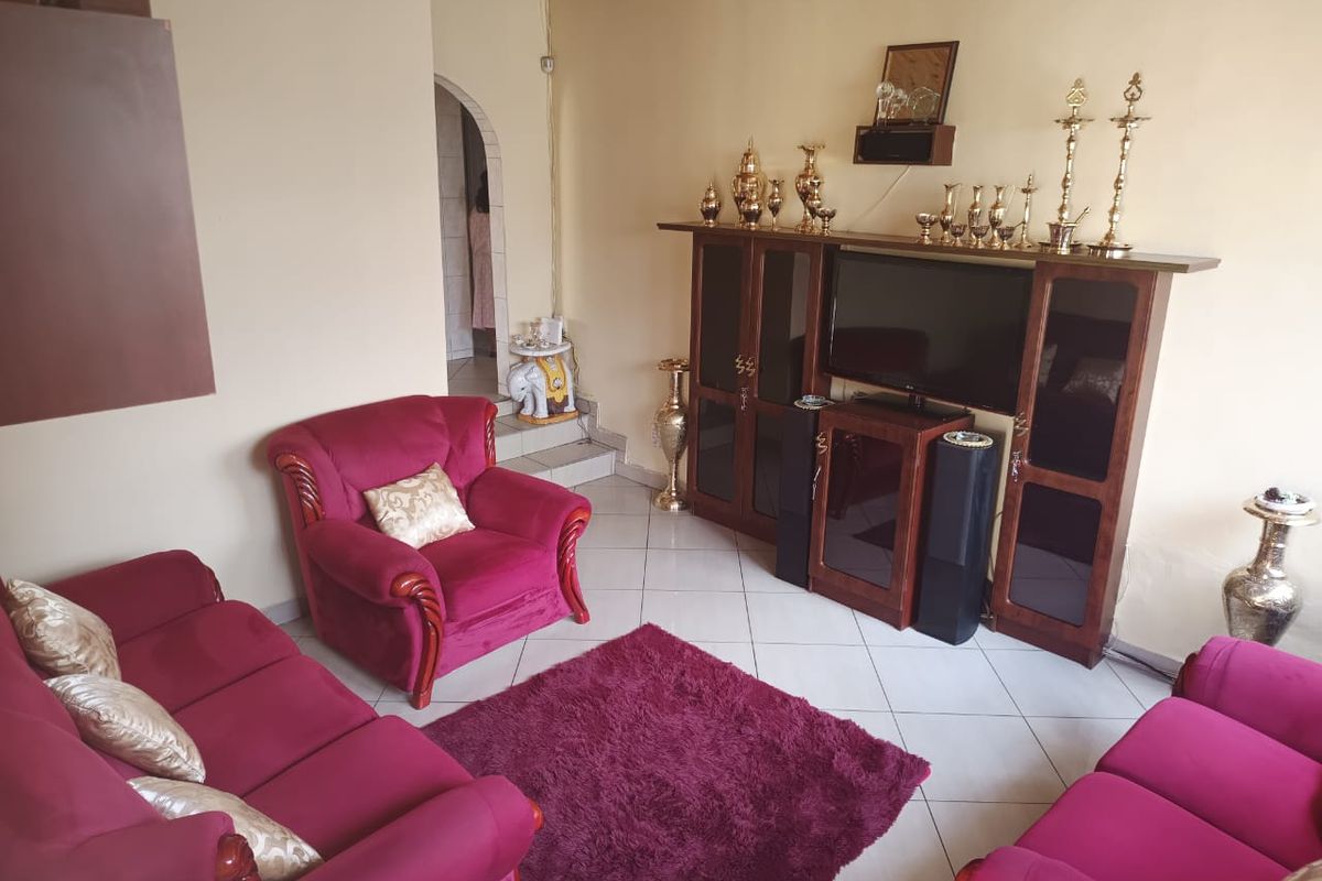 A living room featuring tiled flooring and an arched doorway leading to an adjacent space.