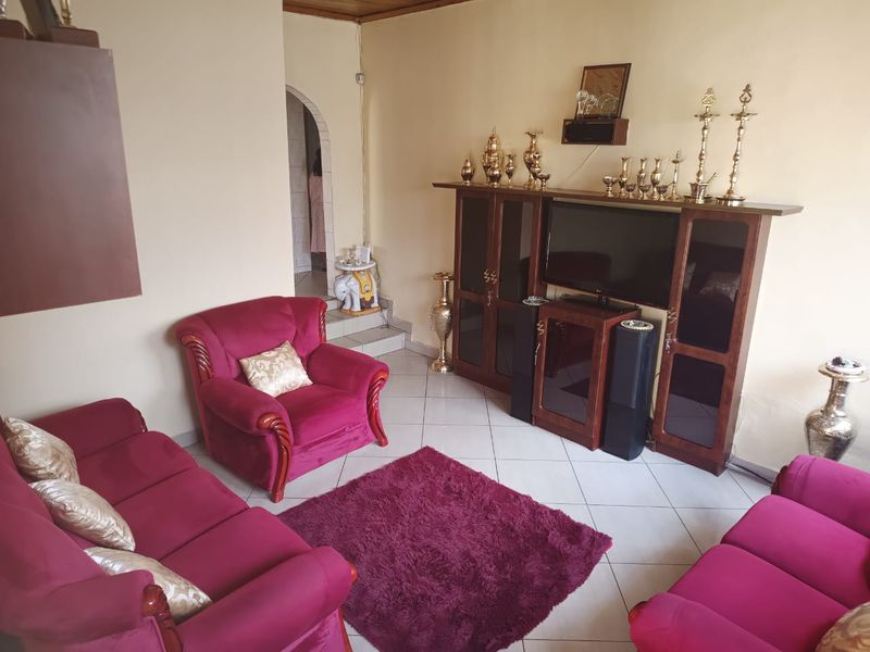 A living room featuring tiled flooring and an arched doorway leading to an adjacent space.