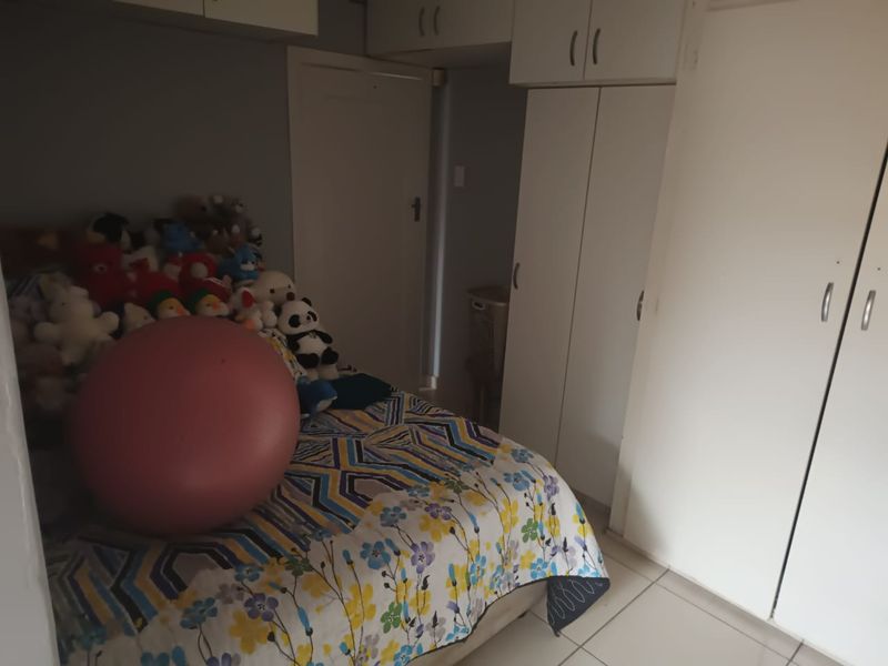 A bedroom featuring built-in cupboards and overhead storage cabinets with tiled flooring.