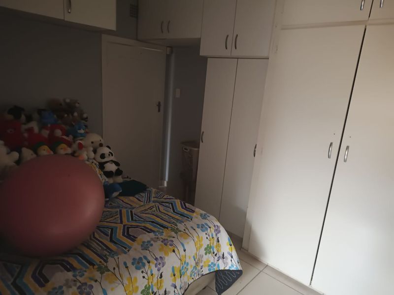 A bedroom featuring extensive built-in cupboard storage and tiled flooring.
