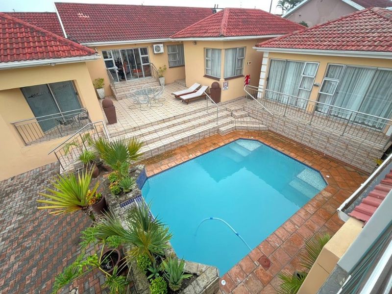 An elevated view of a private courtyard featuring a swimming pool, multi-level tiled patio, and secure stainless steel balustrades.
