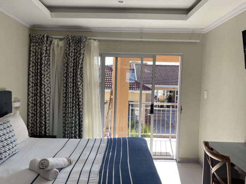 A well-maintained bedroom featuring a tray ceiling, tiled flooring, and sliding glass doors that open onto a private balcony.