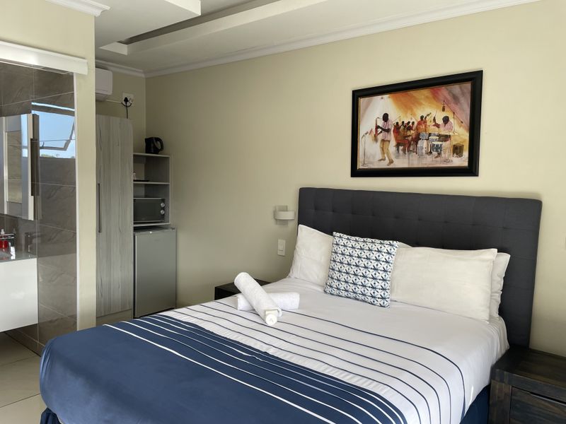 A well-maintained bedroom featuring a neutral color palette, recessed ceiling details, and an integrated en-suite bathroom with modern finishes.