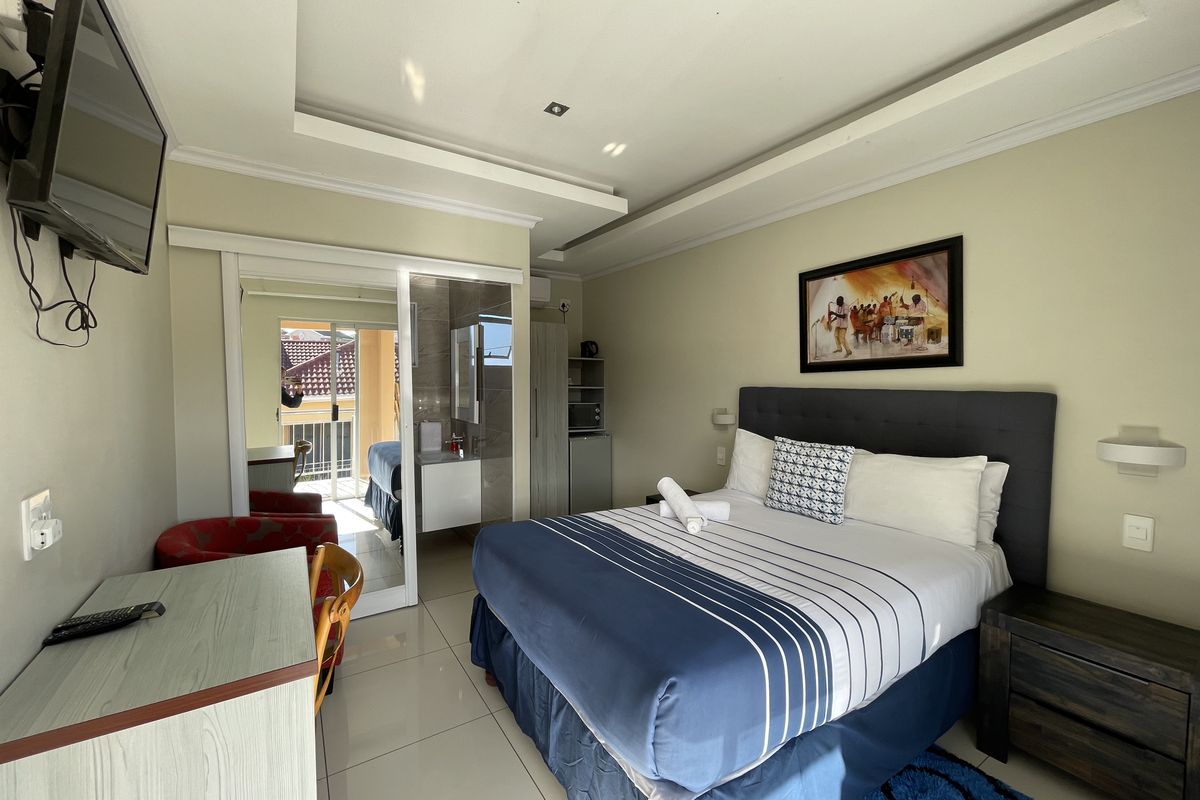 A well-maintained bedroom featuring tiled flooring, a recessed ceiling, and a sliding glass door leading to an outdoor balcony area.