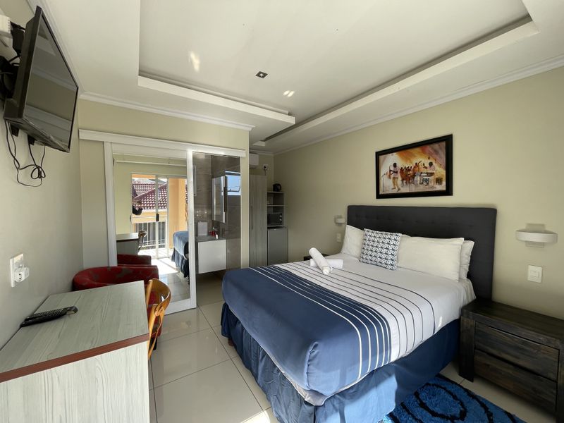A well-maintained bedroom featuring tiled flooring, a recessed ceiling, and a sliding glass door leading to an outdoor balcony area.