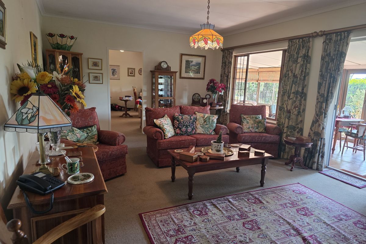 A traditional living room featuring carpeted flooring, a decorative pendant light, and sliding glass doors providing access to an outdoor patio area.