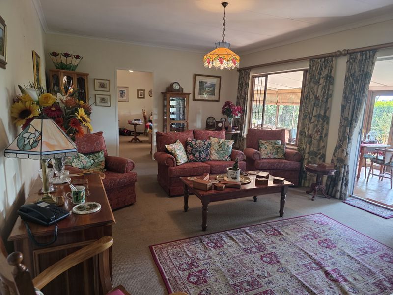 A traditional living room featuring carpeted flooring, a decorative pendant light, and sliding glass doors providing access to an outdoor patio area.