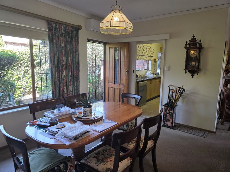 Dining room featuring a sliding glass door with security gate, timber door access to the kitchen, and a wall-mounted split system air conditioner.