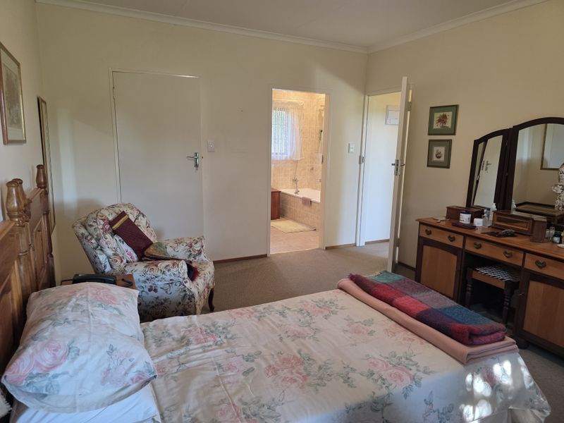 A spacious bedroom featuring carpeted flooring, built-in storage, and direct access to an en-suite bathroom.