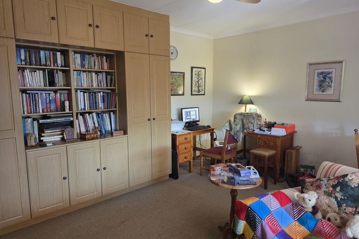 A bedroom featuring extensive built-in wooden cabinetry and a ceiling fan, offering ample storage space.