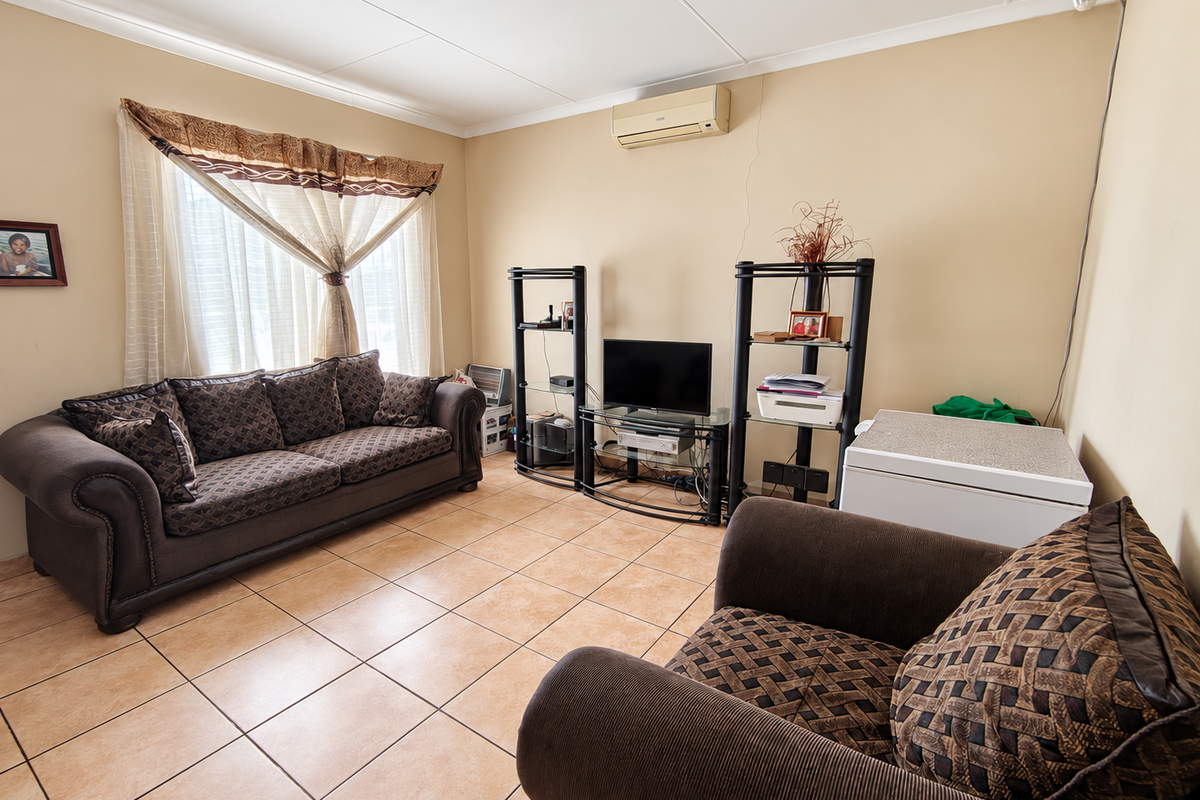 A living room featuring ceramic floor tiles, a wall-mounted air conditioning unit, and coved ceilings, providing a functional space for relaxation.