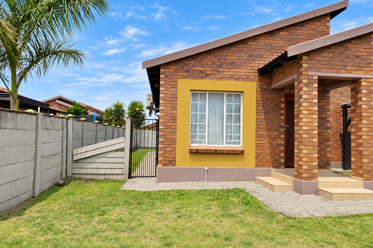 A well-maintained rear exterior view featuring a face brick facade, paved walkway, tiled entrance steps, and a secure precast concrete boundary wall.