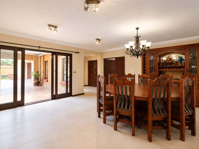 Spacious dining room featuring tiled floors, a built-in wooden display cabinet, and large sliding doors providing seamless access to the outdoor patio area.