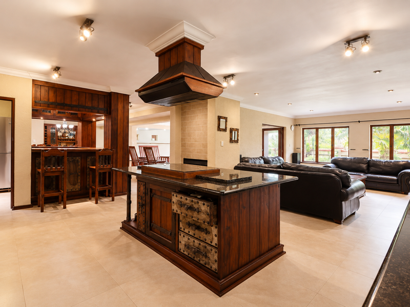 Spacious open-plan living area featuring a large kitchen island with granite countertops, custom wooden cabinetry, and a built-in extractor hood.