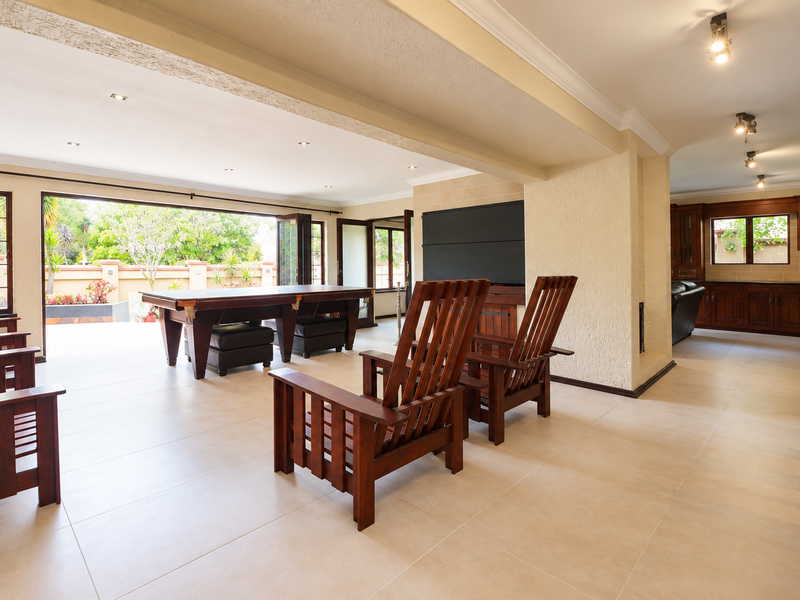 Spacious open-plan living area featuring large bi-fold doors opening to the patio, neutral tiled flooring, and integrated cabinetry with recessed lighting.