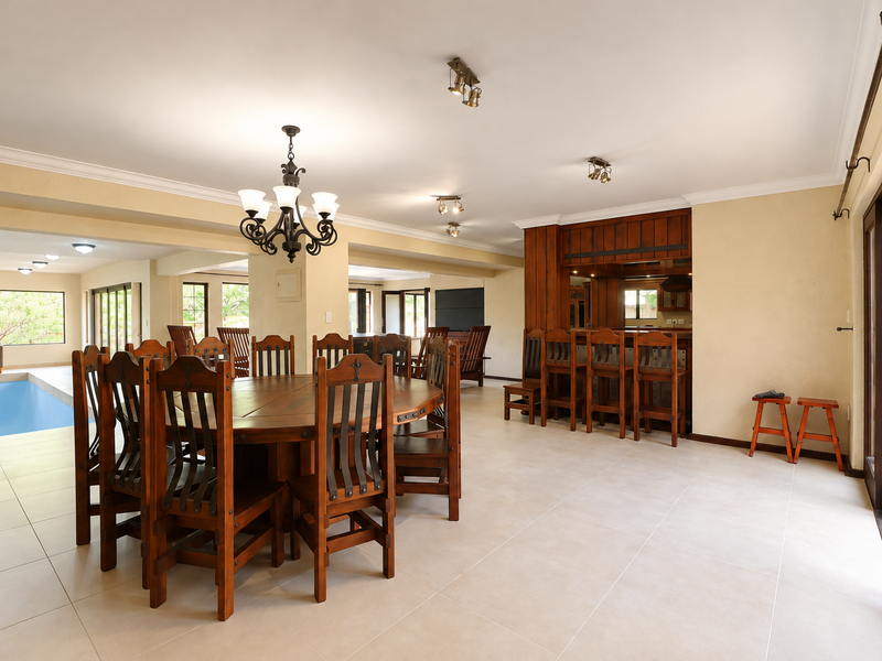 Spacious open-plan living and dining area featuring a built-in wooden bar, tiled flooring, and direct access to an indoor swimming pool.