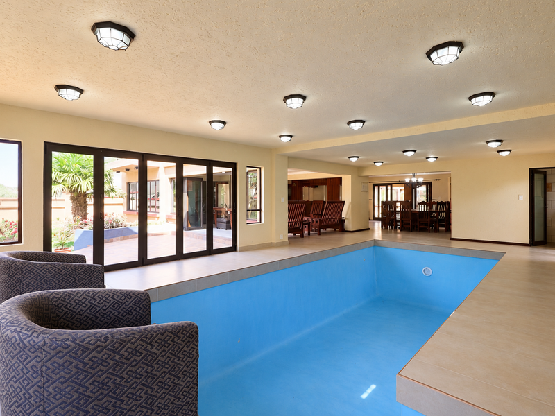 Spacious indoor pool area featuring tiled flooring, recessed lighting, and large bi-fold glass doors providing seamless access to the outdoor patio.