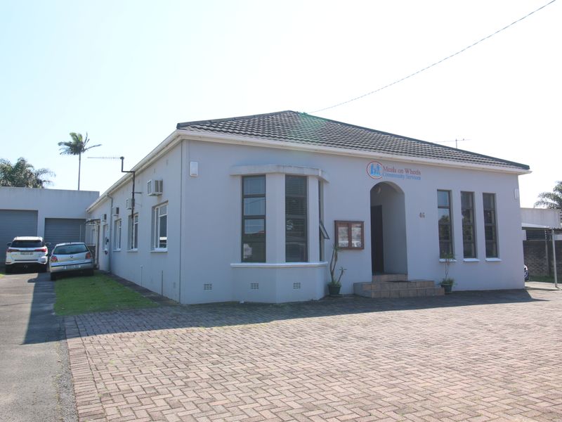 Front elevation of a single-story property featuring a paved driveway, bay window, and a detached garage.