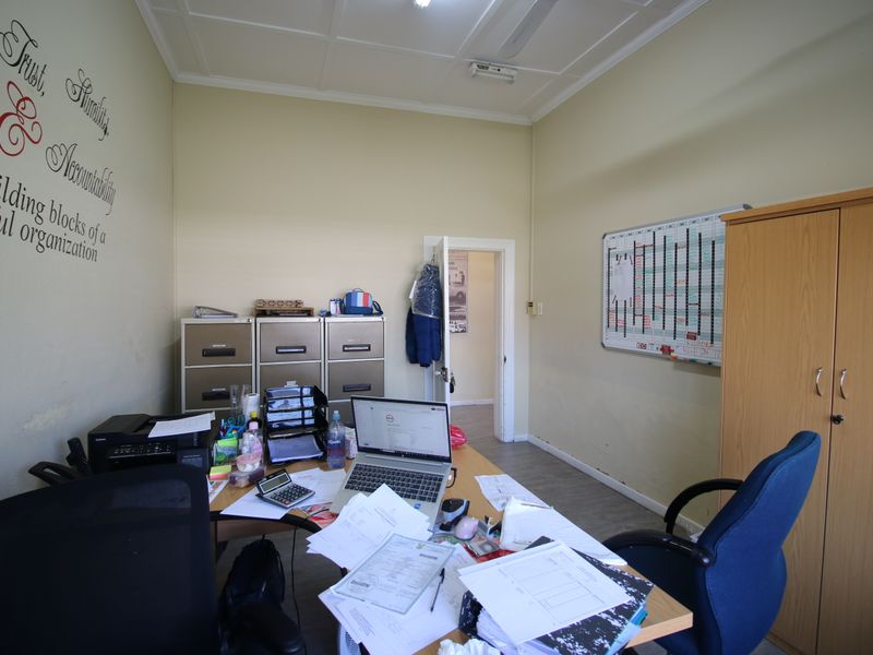 A functional office space featuring neutral walls, tiled ceiling, and practical layout suitable for a professional work environment.