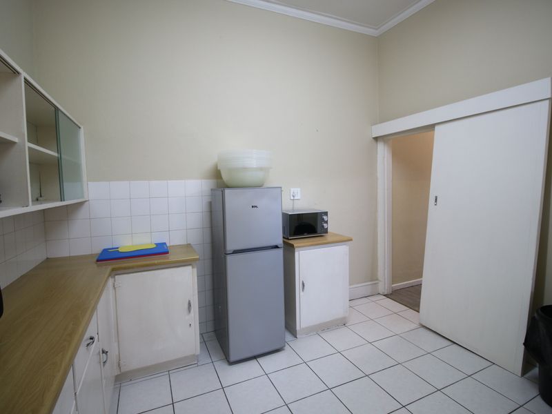 Functional scullery area featuring built-in cabinetry, laminate countertops, tiled splashback, and tiled flooring with a sliding door access.