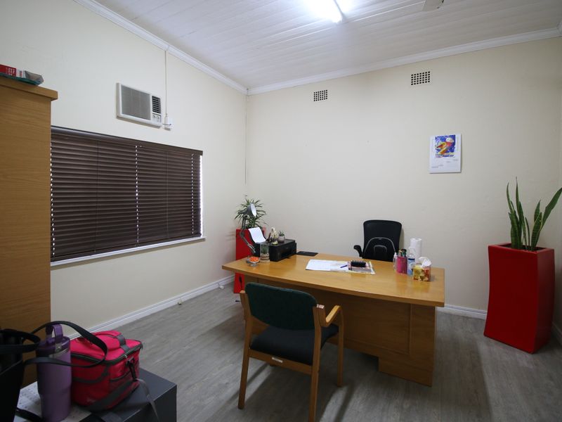 A functional home office space featuring laminate flooring, a timber ceiling, and a wall-mounted air conditioning unit.