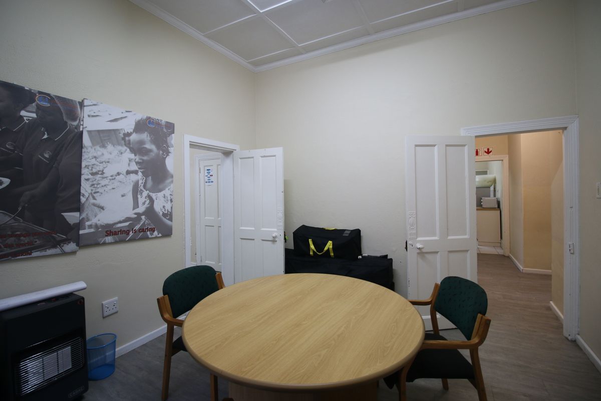 A functional room featuring a panelled ceiling, neutral walls, and multiple doorways leading to adjacent spaces, suitable for a home office or sitting area.