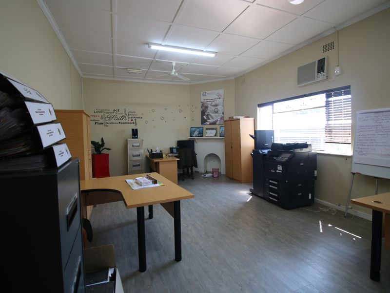 A functional office space featuring laminate flooring, a suspended ceiling, an integrated air conditioning unit, and a decorative fireplace mantel.