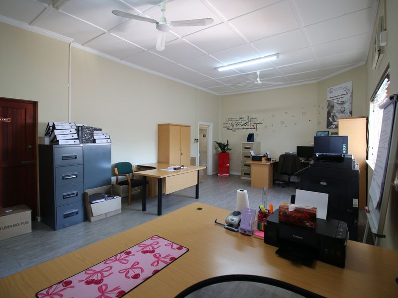 A functional office space featuring laminate flooring, a tiled ceiling with integrated fans, and ample space for multiple workstations.