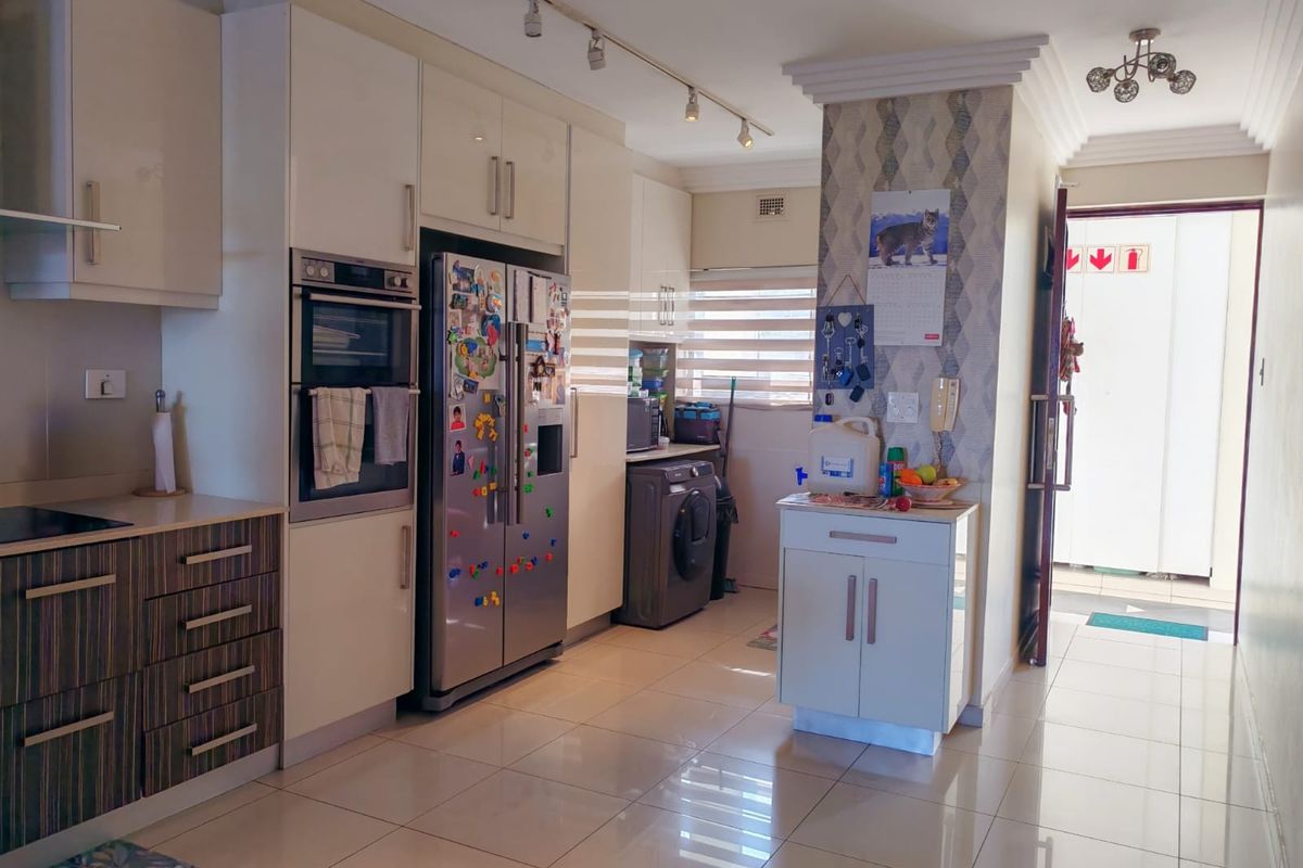 A functional kitchen featuring modern built-in cabinetry, an integrated oven, tiled flooring, and track lighting, providing a clean and practical workspace.