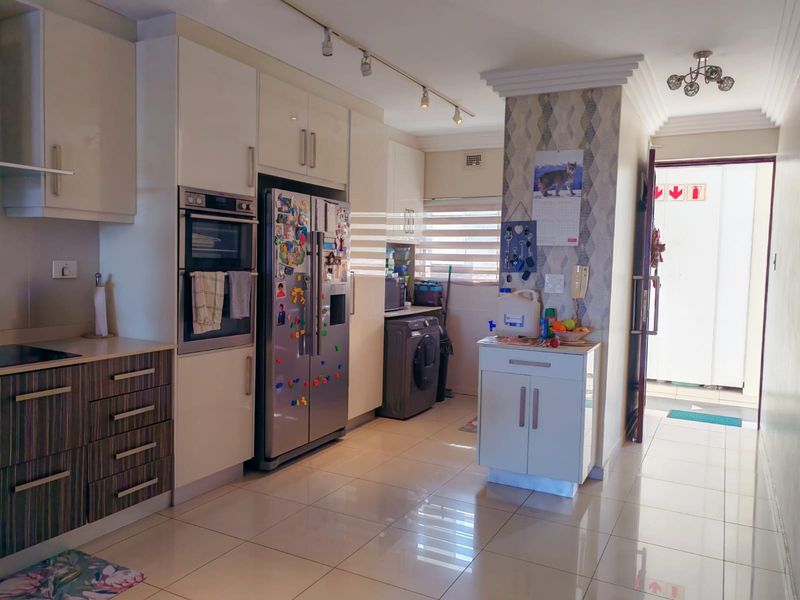 A functional kitchen featuring modern built-in cabinetry, an integrated oven, tiled flooring, and track lighting, providing a clean and practical workspace.