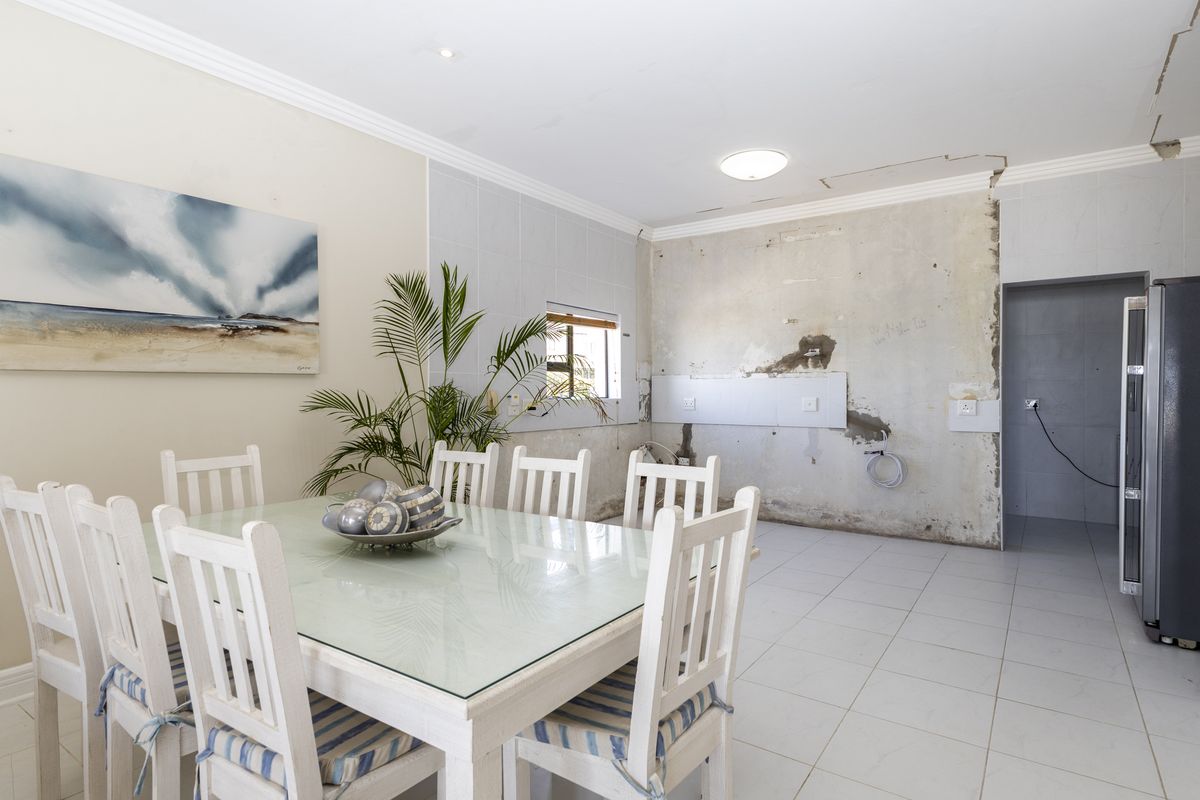 A kitchen area in need of renovation, featuring tiled flooring and exposed wall surfaces, currently used as a dining space.