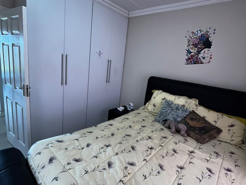A bedroom featuring built-in cupboards, ceiling cornice detailing, and a standard panel door.