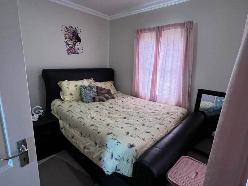 A compact bedroom featuring tiled flooring, ceiling cornice detailing, and a central flush mount light fixture.