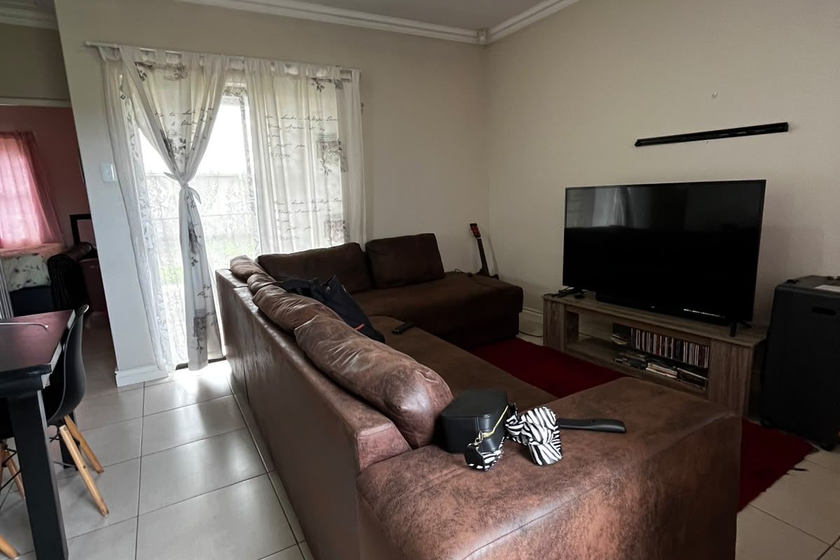 A living room featuring large format floor tiles, a ceiling light fixture, and a sliding glass door providing access to the exterior.